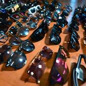 Dozens of sunglasses and glasses pictured diagonally on a wooden floor.