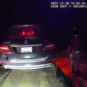 A driver watches while his Mercedes SUV is loaded onto a tow truck. The man told police he was speeding to avoid elk