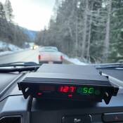 In car Radar system display unit showing 127 km/h. Pickup truck in background.