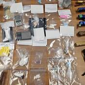 A number of items, including drugs and drug paraphernalia, are displayed on a table.