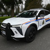 Burnaby RCMP detachment’s new electric patrol vehicle, a white 2024 Chevrolet Blazer EV featuring RCMP logos and decals, parked outside near the detachment.