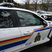 A close-up view of the front of the Burnaby RCMP detachment’s new electric patrol vehicle, a white 2024 Chevrolet Blazer EV featuring RCMP logos and decals, with a standard police cruiser parked in the background.