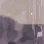 A surveillance photo of a suspect breaking into a building.