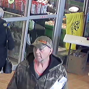 A photo of an unknown male suspect - walking through the entry/exit of a grocery store – while carrying items and a set of keys;