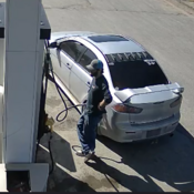 A man with brown wavy hair and a full beard is seen pumping fuel into a vehicle.