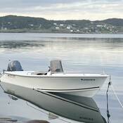 A white vessel, with a Yamaha outboard motor is moored in the water. The HIN on the front of the boat reads “NL2597915” and the “Ocean Fisher” is written on the stern.