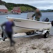 A white vessel sits on a galvanized boat trailer on a boat ramp.