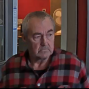 A man in a red and grey plaid shirt exiting a bank.