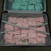 Green and pink-coloured packages containing methamphetamine inside an open suitcase.