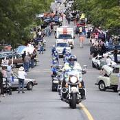 Photo of Tour de Rock riders escorted by police on crowded street