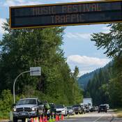A police officer speaks to a driver in traffic at a check stop near the Shambhala music festival