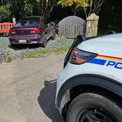 A vehicle that has travelled off the road and crashed into a wood and stone fence