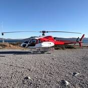 A red and white helicopter on the ground.