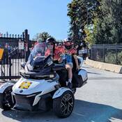 Photo of the Cops for Cancer pace-setter leading the group of riders out of the Mission RCMP detachment, with a very happy junior rider on the back!