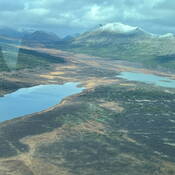 An aerial view of the rugged landscape of Northern B.C., showcasing alpine lakes, broad valleys and the first signs of winter in the mountains.
