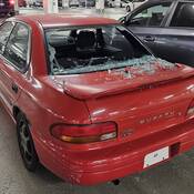 A red Subaru with its rear window smashed.