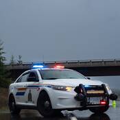 A BC Highway Patrol cruiser at the side of a wet highway in poor driving conditions