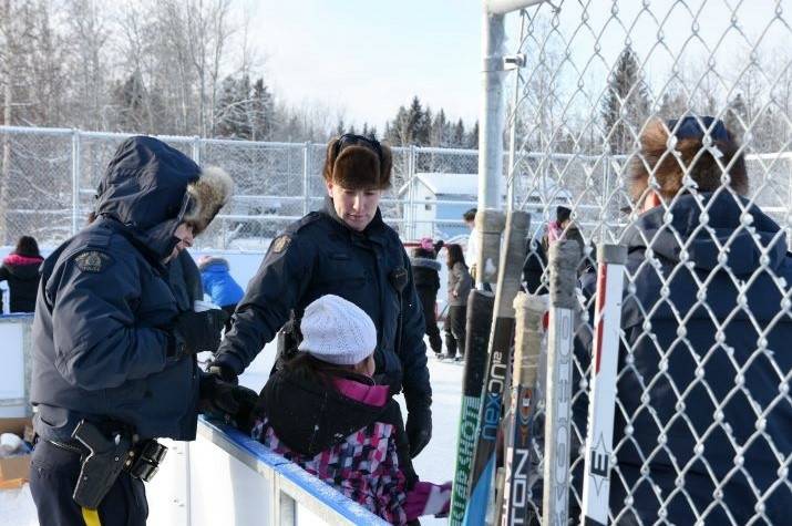 A RCMP officer helps a young skater. 