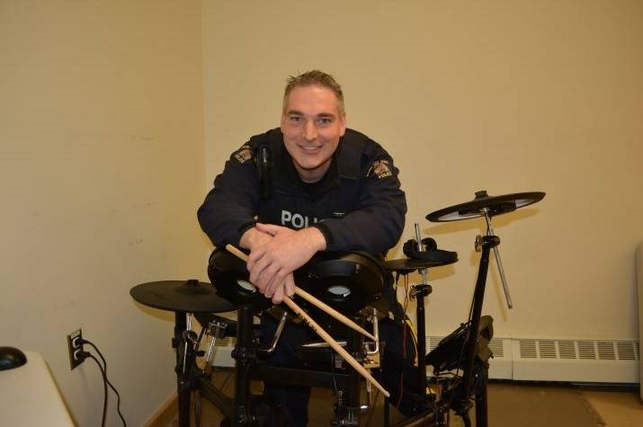 A male <abbr>RCMP</abbr> officer sits behind an electric drum set