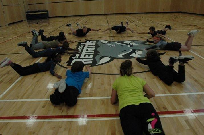 Young people and instructors exercise in a gym.