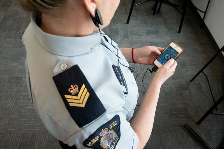 A woman looks at a smartphone that displays a heartbeat. 