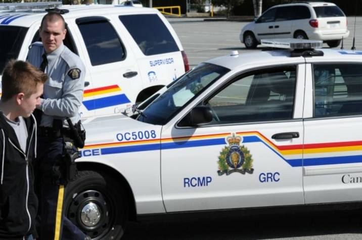 RCMP approach a young man in a parking lot.