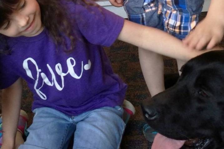 Two children pat dog.
