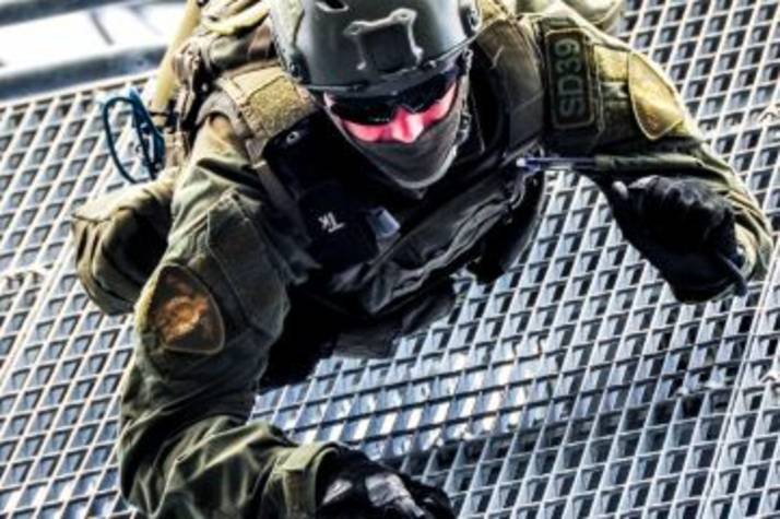 An RCMP Emergency Response Team member climbs down a metal grate during a training exercise.
