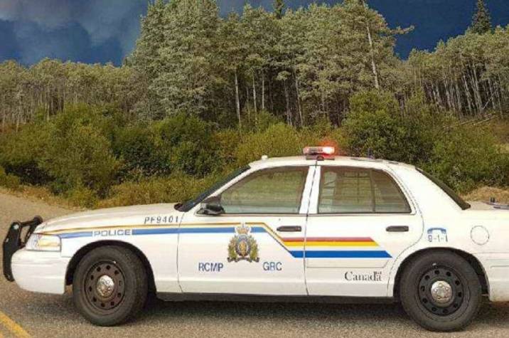 RCMP car on a highway with billowing smoke in the sky.