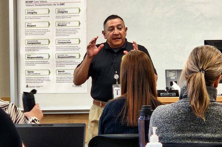 Male instructor speaks to group in a classroom setting.