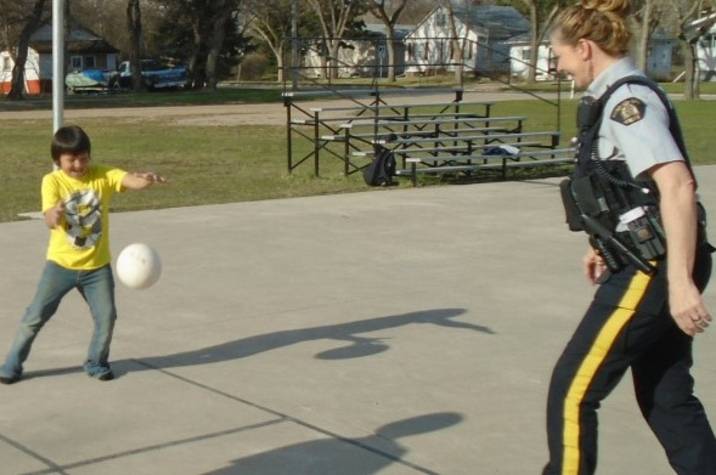 Police officer playing ball with children.