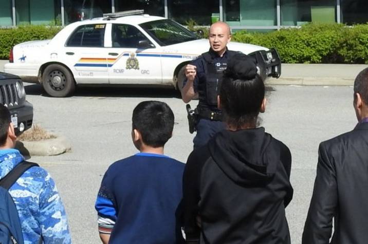 Police officer talks to a crowd of kids in a parking lot