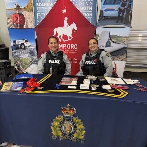 Two police officers in front of booth with RCMP promotional materials | Deux policiers devant un stand présentant du matériel promotionnel de la GRC