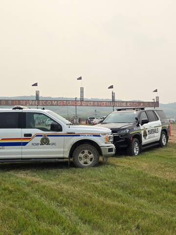 Image of RCMP police truck and Saskatchewan Marshals Service SUV pictured under the 'Welcome to Country Thunder' sign at the gate of the festival grounds.