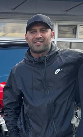 Man wearing a black jacket and black baseball hat
