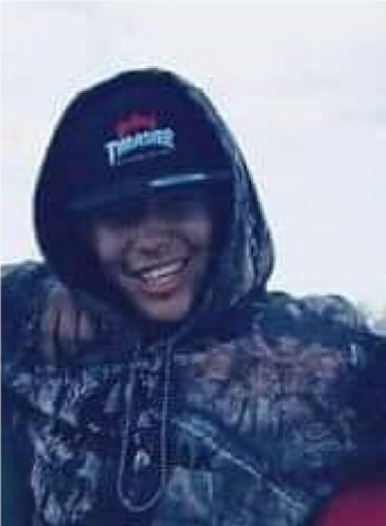 A young male wearing a camo hoodie and a black hat with text. | Un jeune homme portant un sweat à capuche camouflage et une casquette noire avec inscription.