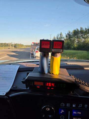 Two Approved Screening Devices showing readings of “Fail” on the dashboard of a BC Highway Patrol cruiser while cars are being prepared for impound in the background