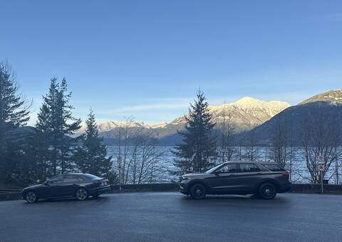A grey Audi preparing to be towed away as a BC Highway Patrol vehicle supervises against the mountain backdrop of the Sea to Sky Highway