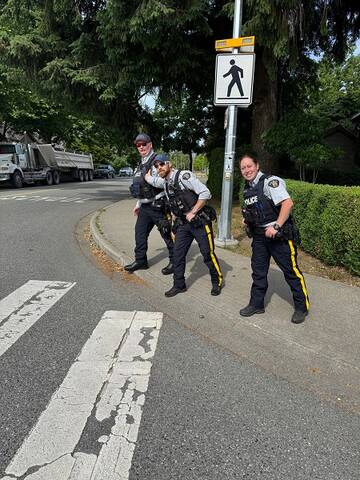 Three uniformed members stand on a street corner