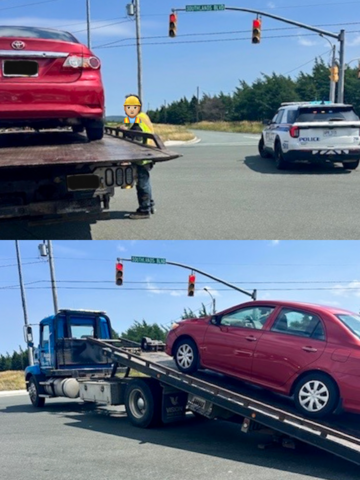 A red four door sedan is loaded on to a tow truck. A marked Royal Newfoundland Constabulary police SUV is seen in the background.