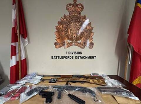 Firearms and other items on table in front of RCMP crest.