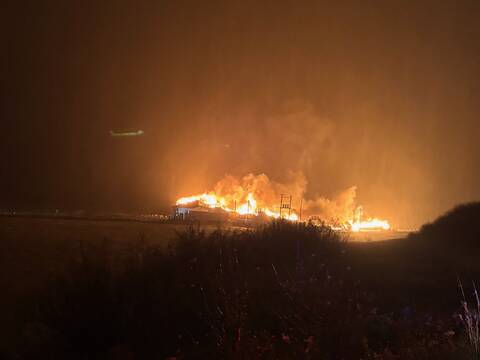 The St. Mary’s Bay Fisheries Inc. fish plant seen at night with flames and billows of smoke emerging from the structure.