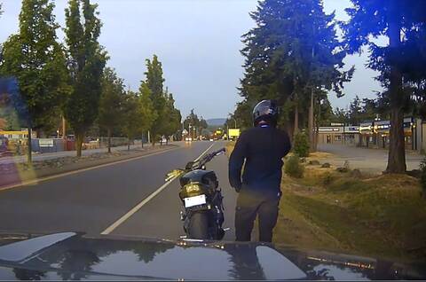 A motorcyclist in front of a BC Highway Patrol vehicle