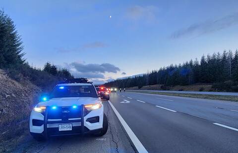 BC Highway Patrol cruisers parked at the side of the highway while investigators work in the background