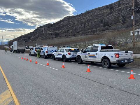 A line of CVSE and BC Highway Patrol officers stopping commercial vehicles on Highway #97 near Osoyoos