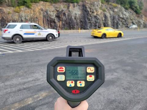 A yellow Porsche stopped in front of a BC Highway Patrol cruiser with a laser reader showing 168 km/h