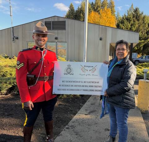 Cpl. Kyle Camalush and Tina Donald holding a sign with the RCMP crest and the Simpcw Nation Crest. The sign says “We recognise one another and will work together.”