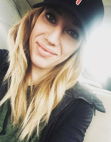 a white young woman with long blond hair wearing a black hat and black jacket