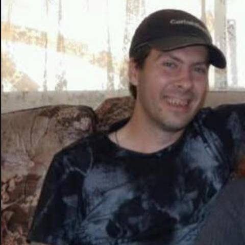Photo of Mitchell Turchyniak sitting on a couch. Face, upper body and legs are in the photo