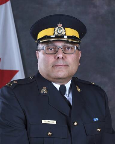 Police officer wearing blue tunic with a white shirt and a tie. He is wearing a blue forage cap with a yellow strip and the RCMP crest.